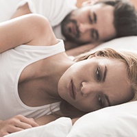 Woman laying awake with sleep partner next to her