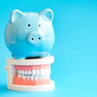 blue piggy bank sitting on top of dentures 