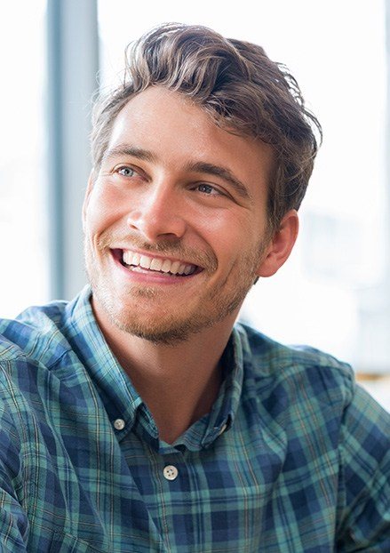 Young man with handsome smile wearing plaid shirt