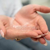 Closeup of woman holding clear aligner