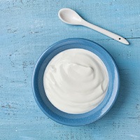 Bird’s eye view of a blue bowl of white yogurt on a blue surface
