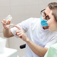 dentist showing a patient a dental implant model