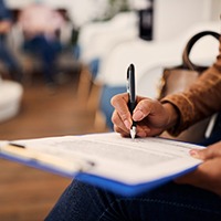 Woman filling out dental insurance form in lobby