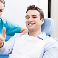 Smiling man in dental chair giving thumbs up