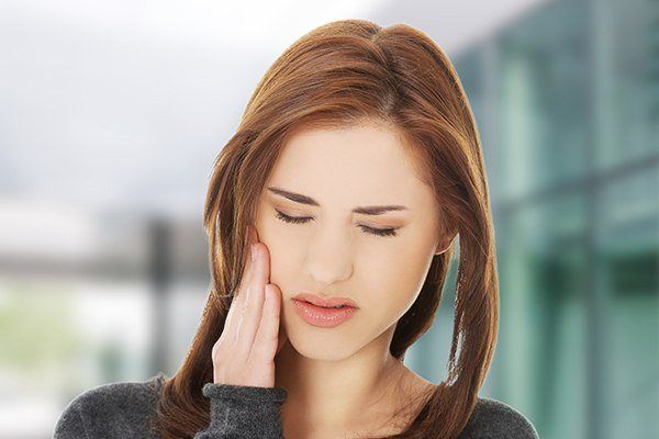 woman holding her cheek in pain