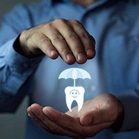 Man holding a tooth under an umbrella