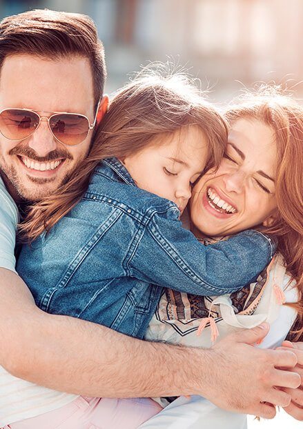 Smiling mother and father hugging their sleeping daughter