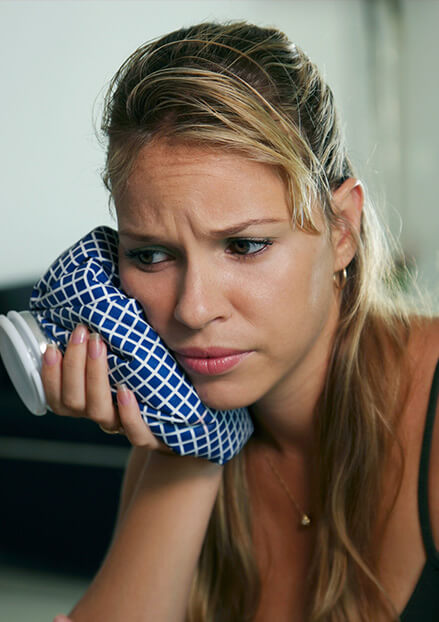 Woman holding ice pack to cheek