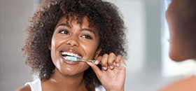 Woman with dark hair brushing teeth