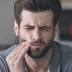 Man in pain while holding cheek