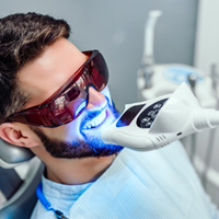 Man having UV light applied to teeth whitening in dental office
