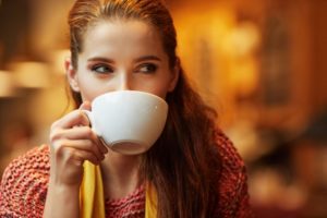 A woman sipping from a mug.