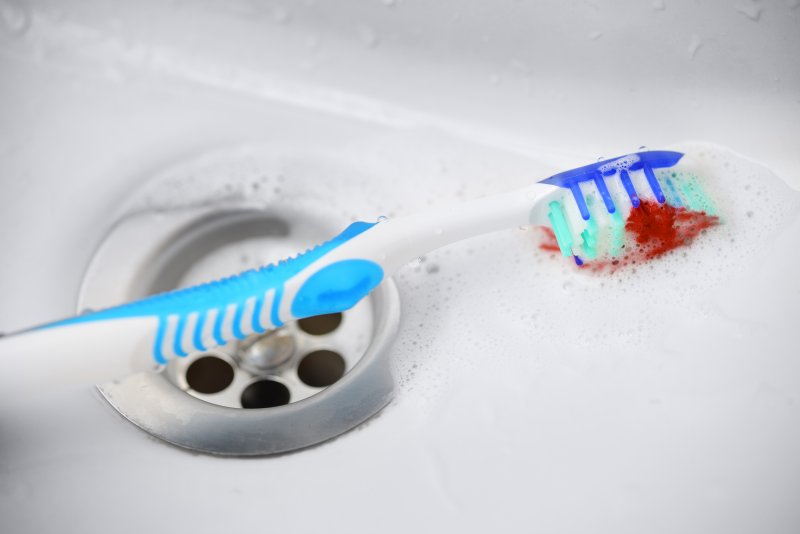 a toothbrush lying in the sink with blood on it