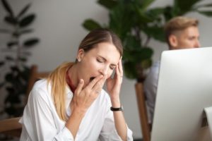 Woman tired from sleep apnea at computer