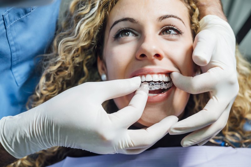 Dentist helping patient put on Invisalign