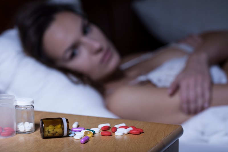 Woman lying awake looking at sleeping pills on table