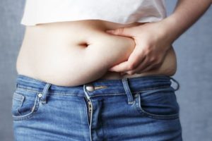 person grabbing their belly fat, concerned about weight gain and sleep apnea