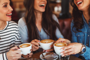 Three women drinking coffee and smiling