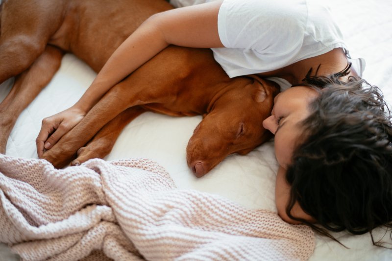 Woman sleeping with dog in bed.