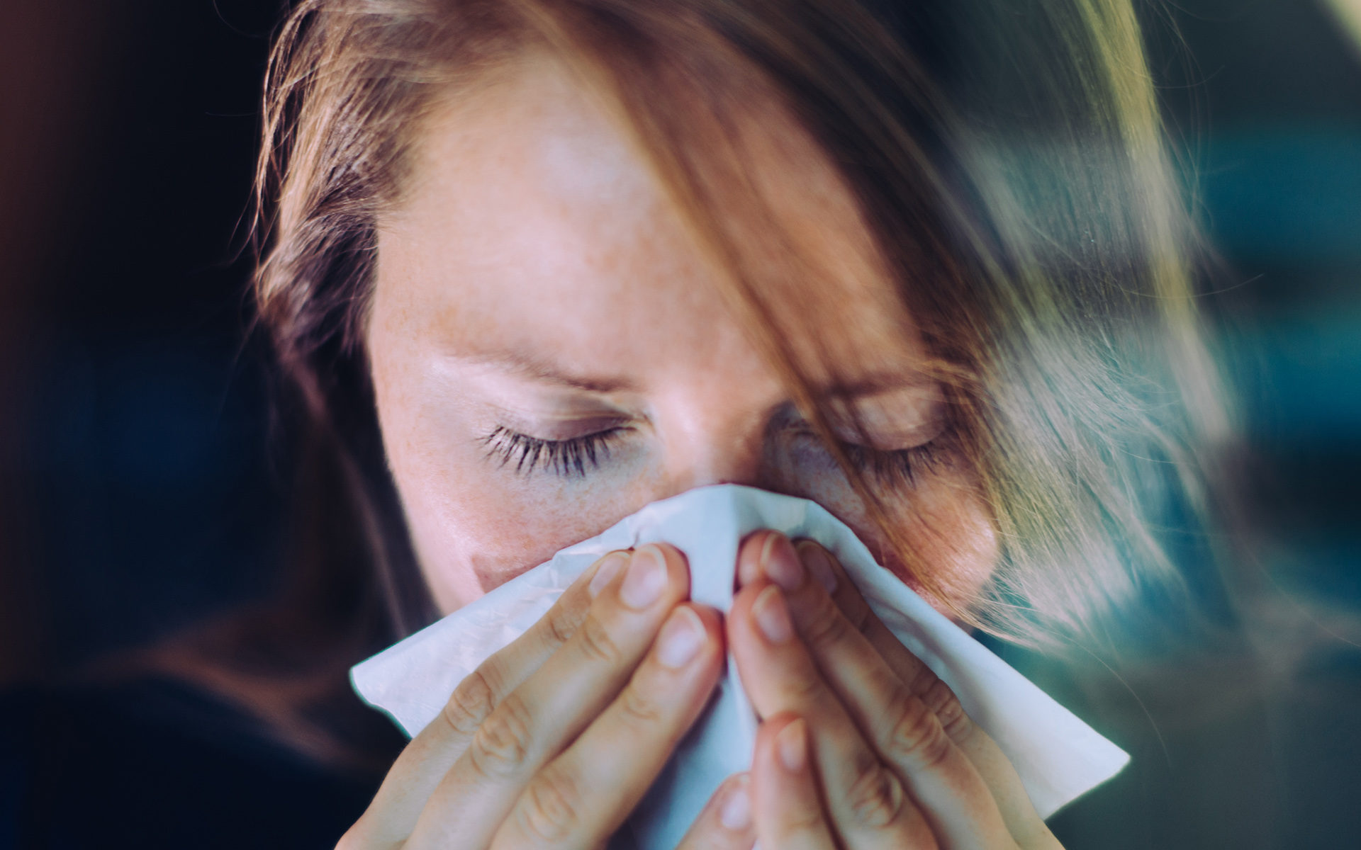 person suffering from seasonal allergies blowing nose