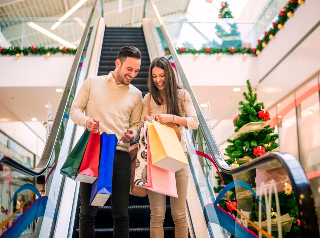 Couple smiling while holiday shopping at the mall