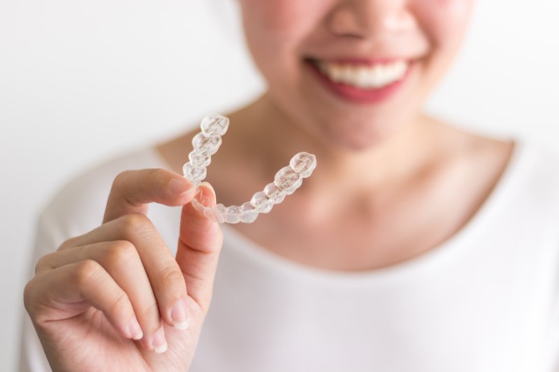 Young woman holding her Invisalign aligner