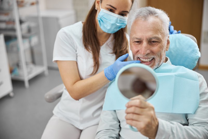 An older man admiring his new dental implants