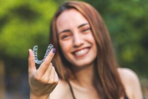 Woman holding up her Invisalign tray